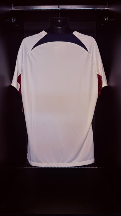 A white athletic t-shirt displayed on a black mannequin torso against a dark background. The shirt features a dark navy blue yoke at the shoulders and maroon side panels.