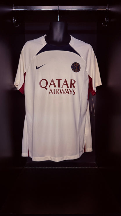 A white Paris Saint-Germain soccer jersey with 'QATAR AIRWAYS' sponsor text, displayed on a black mannequin torso against a dark background.